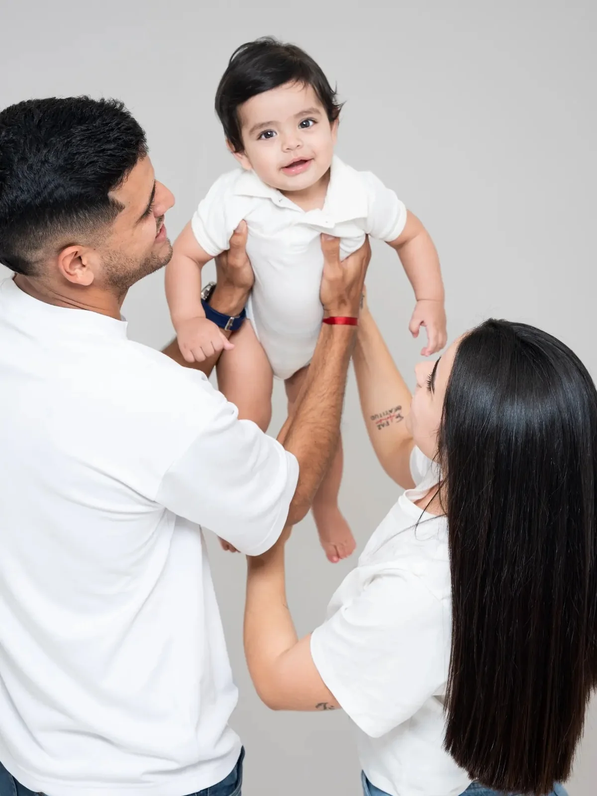 Papá levantando a su bebé mientras mamá sonríe