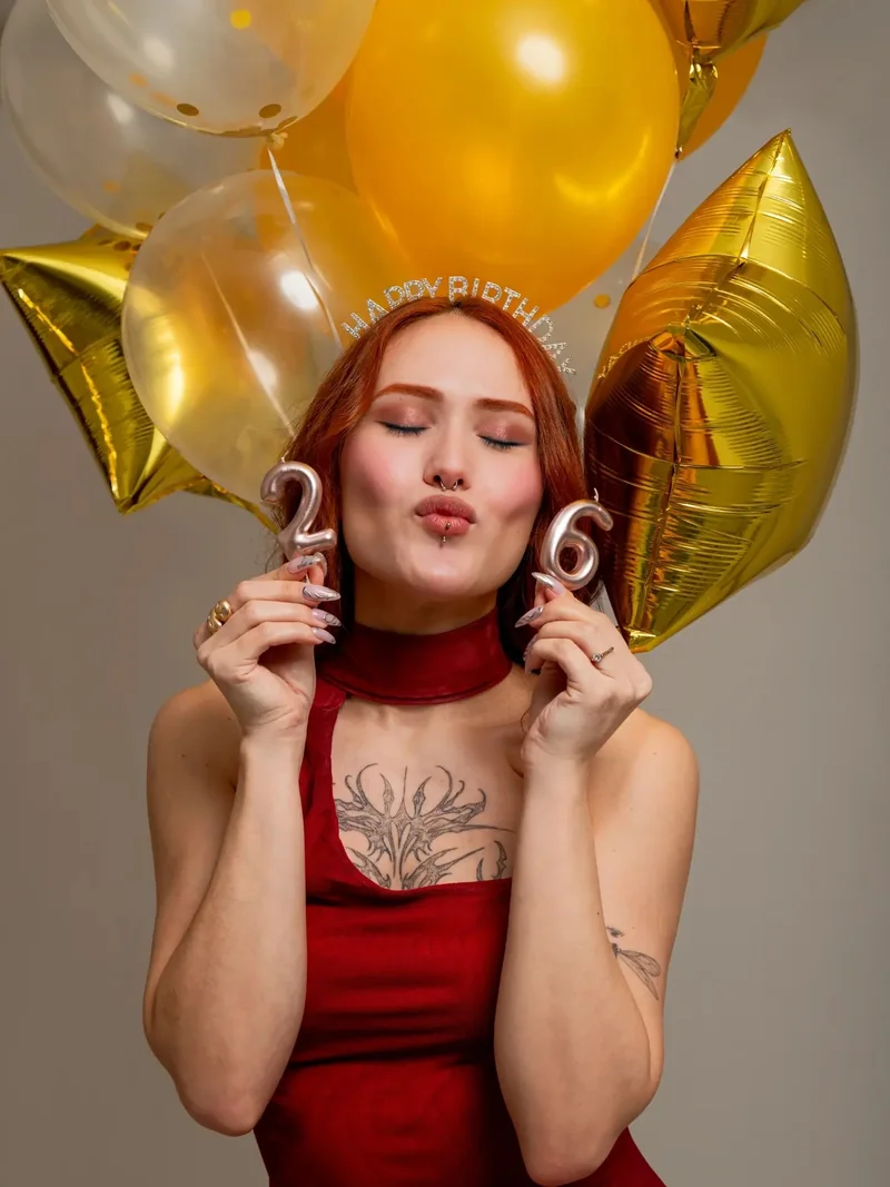 Mujer con vestido rojo y globos dorados en su book de cumpleaños