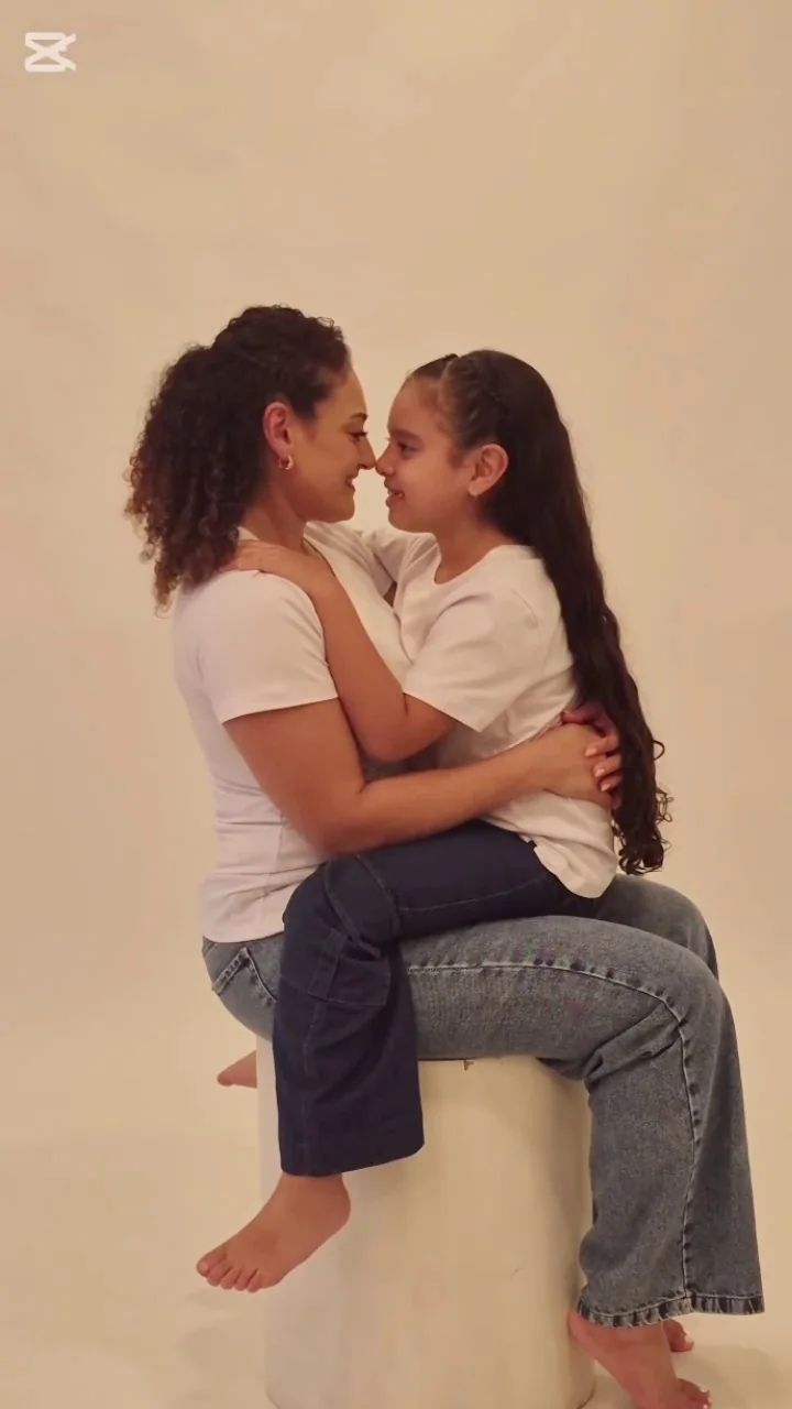 Mamá sentada abrazando a su hija en el estudio